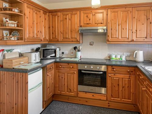 a kitchen with wooden cabinets and a stove top oven at Middle Cottage in Thirsk