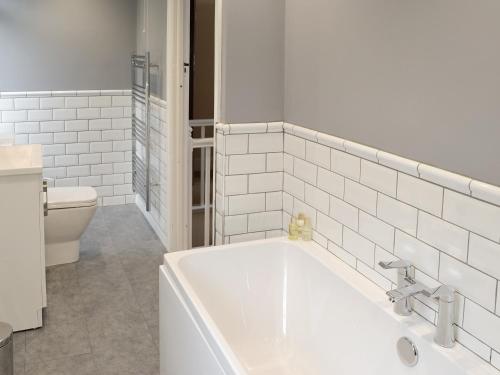 a white bathroom with a tub and a toilet at Hillside in Praa Sands