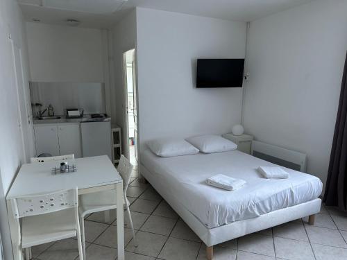 a white bedroom with a bed and a table at La campagne à 5 minutes de Tours. in Fondettes