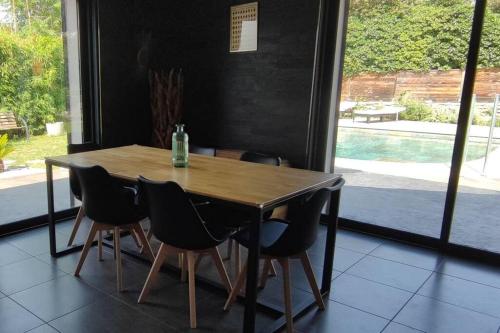 - une table en bois avec des chaises et une bouteille de verre dans l'établissement Maison tout confort en garrigue, à Boisseron