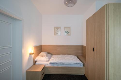 a small bedroom with a bed and a cabinet at Stará škola - Alte Schule, Loučná in Jindřichovice