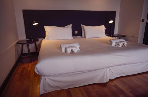 a large white bed with two stuffed animals on it at Hotel Hita "Nature Experience" for all in Navacerrada