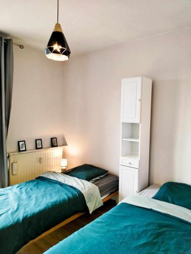 une chambre avec deux lits et une étagère dans l'établissement Appartement Barbieux - Roubaix - 15min de Lille, à Roubaix