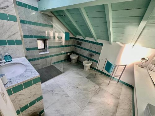ein großes Bad mit einem Waschbecken und einem WC in der Unterkunft Grosszügige Dachwohnung in Tessiner Altbau in Monte Ceneri
