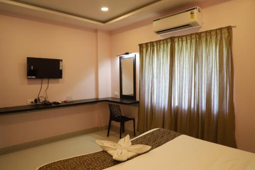 una habitación con una cama, un escritorio y un televisor en vimo boutique hotel, en Auroville
