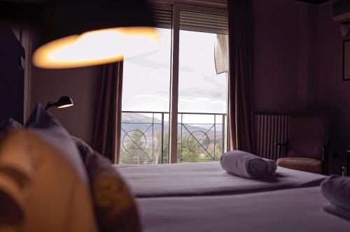 a bedroom with a bed and a large window at Hotel Hita "Nature Experience" for all in Navacerrada