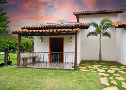 a white house with a palm tree in the yard at Pousada Vila do Lago in Capitólio