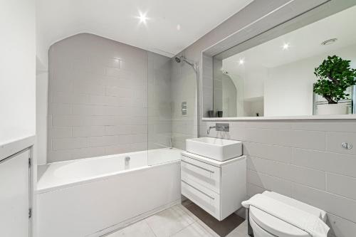 a white bathroom with a tub sink and a toilet at The Old Street Luxury Flat in London