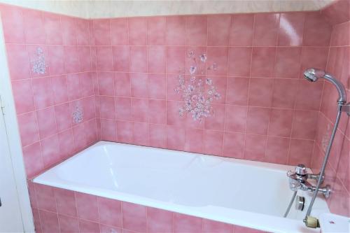 La salle de bains carrelée de rose est pourvue d'une baignoire. dans l'établissement Maison avec WIFI, jardin, à 900m de la plage de Trestraou à PERROS-GUIREC Ref 849, à Perros-Guirec