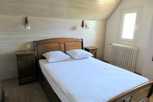 une chambre avec un lit avec deux oreillers blancs dans l'établissement Maison avec WIFI, jardin, à 900m de la plage de Trestraou à PERROS-GUIREC Ref 849, à Perros-Guirec