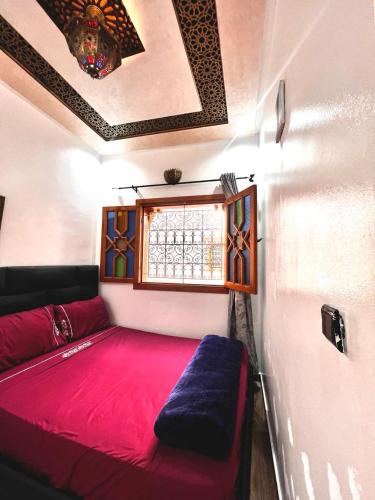 a small room with a red bed and a window at Riad Najiba in Rabat