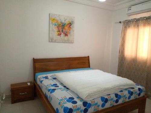 1 cama en un dormitorio con una foto en la pared en Appartement meublé en Dakar