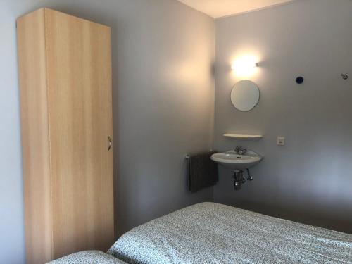 Schlafzimmer mit einem Bett, einem Waschbecken und einem Spiegel in der Unterkunft d'Uyterwaerde in Leut