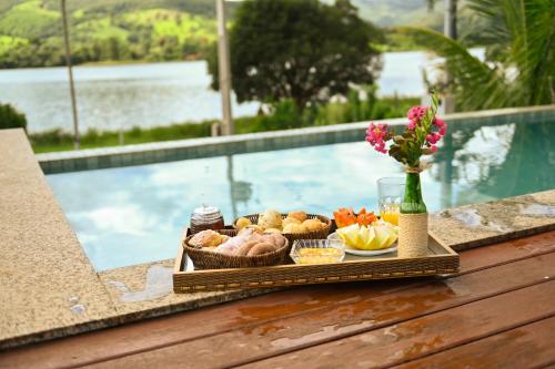 a tray of food on a table next to a pool at Pousada Vila do Lago in Capitólio