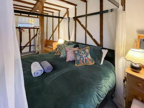 um quarto com uma cama verde com almofadas em The Cottage At Harple Farm em Detling