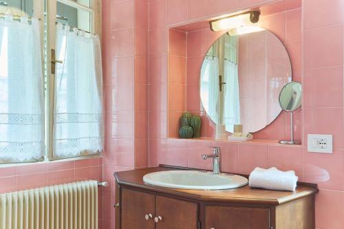 ein rosafarbenes Bad mit einem Waschbecken und einem Spiegel in der Unterkunft Villa Brunelli in Riva del Garda