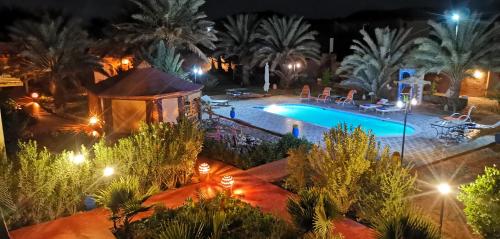 a pool with a gazebo and palm trees at night at Oasis Tilogui in Zagora