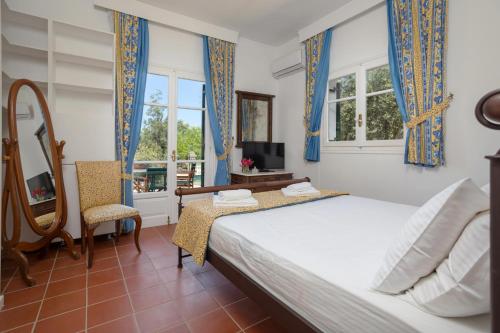a bedroom with a bed and a tv and windows at Villa Alkis - Spacious Pool Retreat in Zakynthos