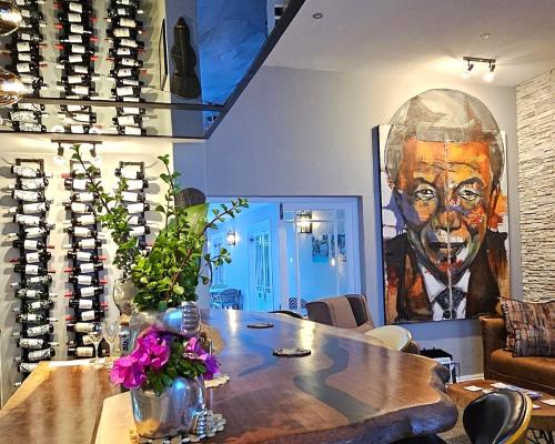 une chambre avec une table et une peinture d'un homme dans l'établissement Fleur du Soleil Luxury Guesthouse, à Franschhoek