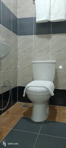 a bathroom with a toilet and a sink and towels at Hotel Blue Orchid in Bayan Lepas