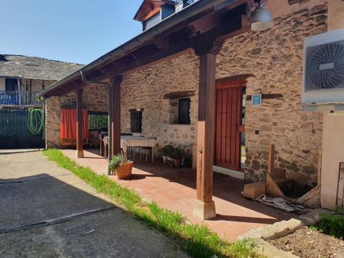 a stone house with a red door and a patio at El Bierzo Oro en el Camino in Villaverde de la Abadía