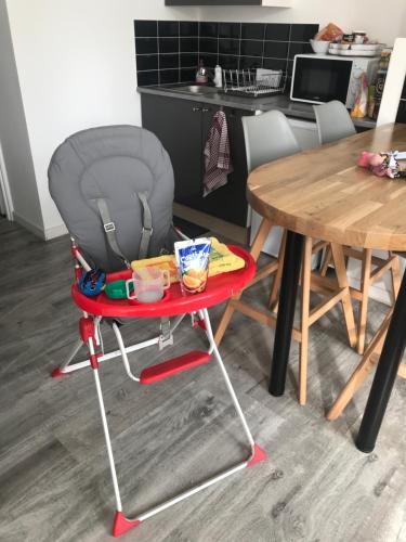 a red high chair with a table and a table at maison julius aeroport tillé 2 a 4 personnes in Tillé