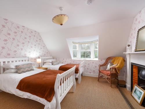 a bedroom with two beds and a fireplace at The Gardeners Cottage in Methven