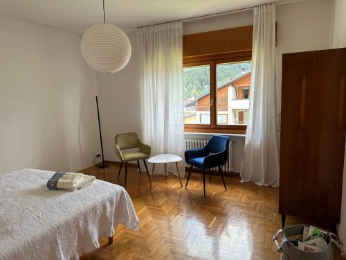 1 dormitorio con 1 cama, 2 sillas y ventana en Ciasa Mia Nelle Dolomiti en Pieve di Cadore