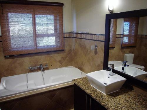 a bathroom with a tub and a sink and a mirror at Palazzo Gardens -Self catering Guesthouse in Swakopmund