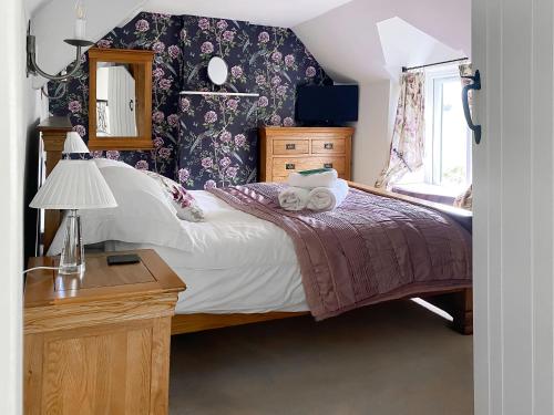 a bedroom with a bed with a dresser and a mirror at Folly Cottage in Avening