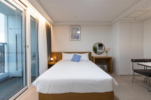 a bedroom with a large white bed and a window at Blue12 Yangyang Surf in Yangyang