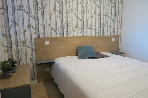 - une chambre avec un lit et un mur arboré dans l'établissement Bel Appartement neuf plage de Trestraou à PERROS-GUIREC - Ref 862, à Perros-Guirec