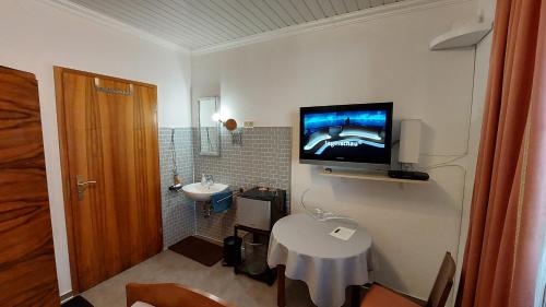 ein Badezimmer mit Waschbecken und einem Fernseher an der Wand in der Unterkunft Fremdenzimmer Familie Förster in Villingen-Schwenningen