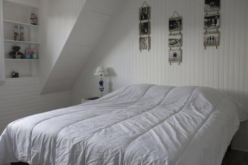 - un lit blanc dans une chambre blanche avec des photos sur le mur dans l'établissement Maison de charme avec jardin clos, terrasse à PERROS-GUIREC - Ref 868, à Perros-Guirec