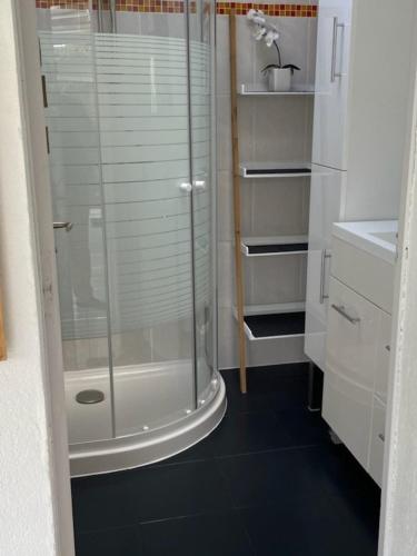 La salle de bains est pourvue d'une douche et d'un sol noir. dans l'établissement Maison de charme avec jardin clos, terrasse à PERROS-GUIREC - Ref 868, à Perros-Guirec