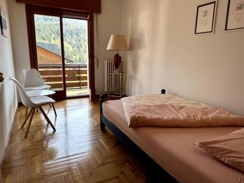 um quarto com uma cama, uma cadeira e uma janela em Ciasa Mia Nelle Dolomiti em Pieve di Cadore