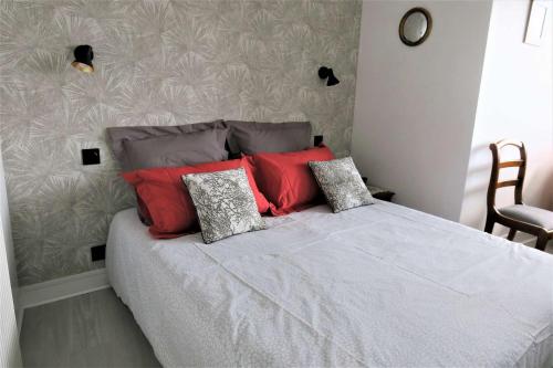 sypialnia z łóżkiem z czerwonymi i szarymi poduszkami w obiekcie Bel appartement avec loggia et balcon VUE SUR MER à PERROS-GUIREC - Réf 874 w mieście Perros-Guirec