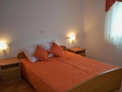 um quarto com uma cama com lençóis e almofadas laranja em Appartement in Banjole mit Garten und Grill em Banjole