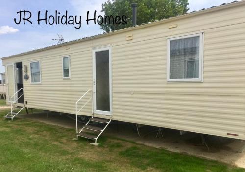 a mobile home with a porch and a ladder on it at J.R. Holiday Homes in Saint Osyth