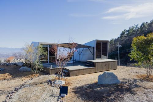 a house on the side of a hill with trees at ALPS LAPS withTENAR in Kami-iino