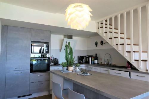 une cuisine avec une grande île dotée de chaises et d'un lustre dans l'établissement Maison avec Terrasse Superbe Vue Mer plage de Trestraou - ref 907, à Perros-Guirec