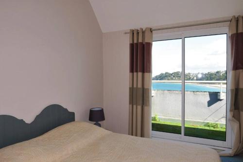 une chambre avec un lit et une grande fenêtre dans l'établissement Maison avec Terrasse Superbe Vue Mer plage de Trestraou - ref 907, à Perros-Guirec