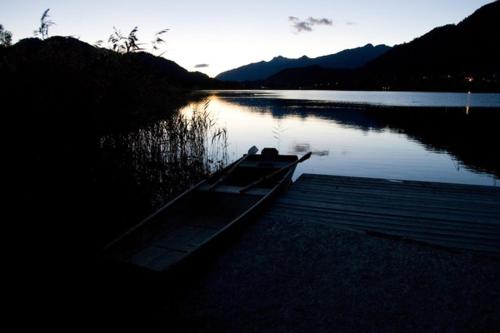 a boat sitting on the shore of a lake at Haus Garz in Weissensee