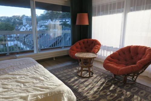 - une chambre avec deux chaises, un lit et une fenêtre dans l'établissement Appartement VUE PANORAMIQUE MER plage de Trestraou à PERROS-GUIREC - Réf 911, à Perros-Guirec