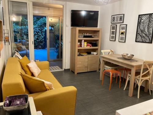 un salon avec un canapé jaune et une table dans l'établissement Appartement en rez-de-jardin avec terrasse, à La Grande Motte