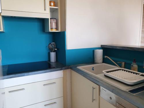kuchnia ze zlewem i niebieską ścianą w obiekcie Bel appartement rénové au centre-ville de PERROS-GUIREC - Réf 920 w mieście Perros-Guirec