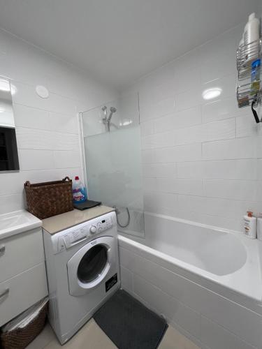 La salle de bains blanche est pourvue d'un lave-linge et d'une baignoire. dans l'établissement Appt à 10 min de Paris, 15 min a pied du SDF, à Saint-Denis