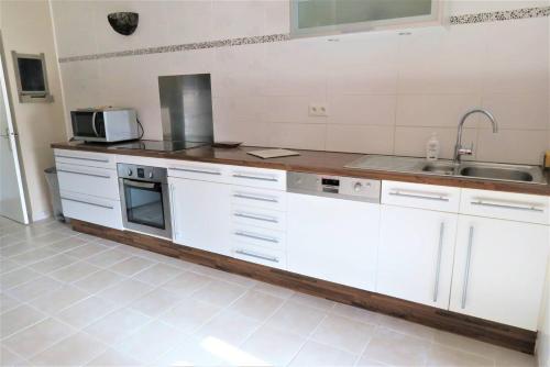 une cuisine avec des armoires blanches et un évier dans l'établissement Maison bretonne avec jardin clos au centre de PERROS-GUIREC - Réf 928, à Perros-Guirec