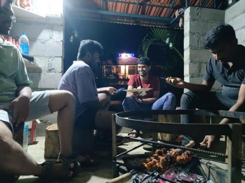 a group of people sitting around a grill at Vasu estate stay in Madikeri