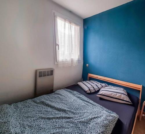 - une chambre dotée d'un mur bleu et d'un lit avec des oreillers dans l'établissement Petite perle, à 2 pas de la gare et du centre, à Sète